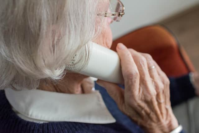 An elderly woman takes a phone call