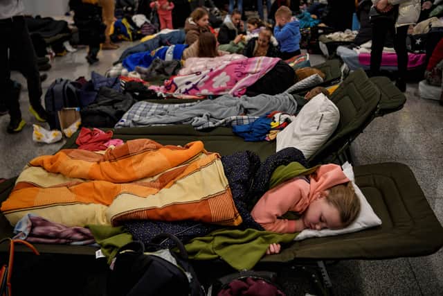 Refugees from Ukraine rest at a temporary shelter in the main train station of Krakow on March 6, 2022, as they wait to be relocated to other temporary accomodations in Poland or abroad.  (Photo by Louisa GOULIAMAKI / AFP)