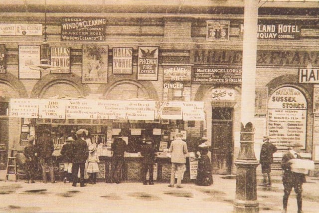 An interior view from 1905 of Eastbourne railway station, with news stand and enamel hoardings.