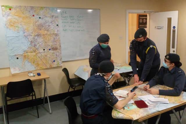 Cadets taking navigational training classes, studying aerial charts and Ordnance Survey maps to plot routes as part of their syllabus training. (Crown Copyright 2022)