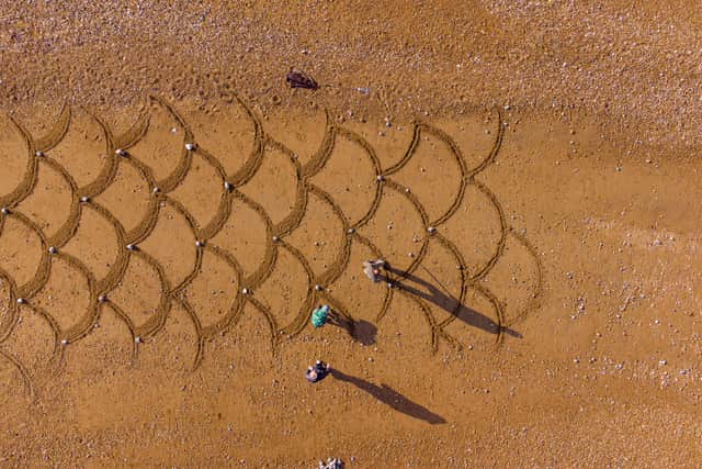 The making of the fish scale design sand drawing by Simon Perlaki. Picture from Robert Trifan (RT Photography). SUS-210428-112042001