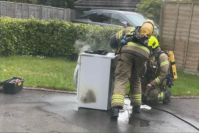 Firefighters check over the burnt out tumble dryer