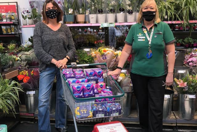 Alison Whitburn, community champion at Morrisons Littlehampton, presents Rachel Hunt from On Point with more than 60 packs of sanitary towels for her community project