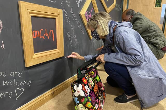 Writing messages of welcome for refugees in Chichester on the chalkboard wall. Photo by Liz Fawkes