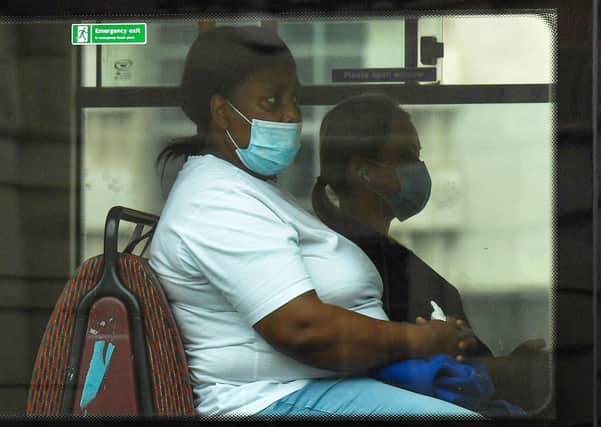 A passenger wears a face-mask as she travels on a bus (Photo by JUSTIN TALLIS/AFP via Getty Images)