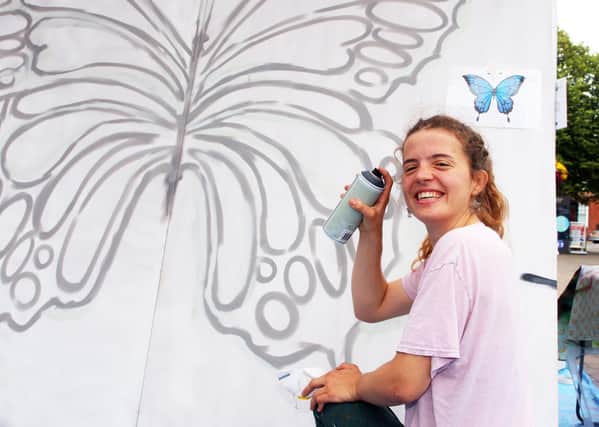 Zara Wilkins about to spray paint a butterfly onto the insect themed mural for Littlehampton town centre. Photo by Derek Martin Photography