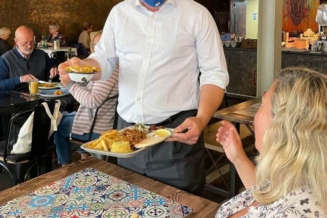 Tim Loughton MP for East Worthing and Shoreham serving customers food at The Fat Greek Taverna in Portland Road, Worthing