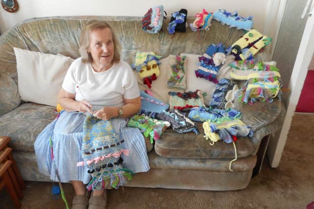 Jill Allen-King with muffs she knits for patients with dementia. SUS-210410-090336001