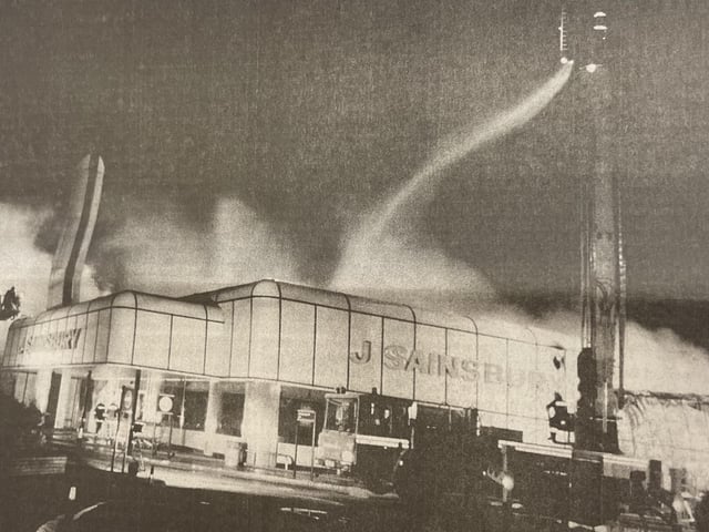 A lone fireman battles with the flames from above as they spread through the roof.