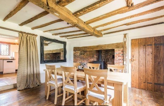 The impressive split-level dining room, with inglenook fireplace and woodburning stove, has views over the beautifully landscaped parterre garden.