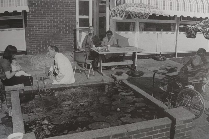 Dr Kingsbury with visitors relaxing by the fish pond at the hospice in Columbia Drive