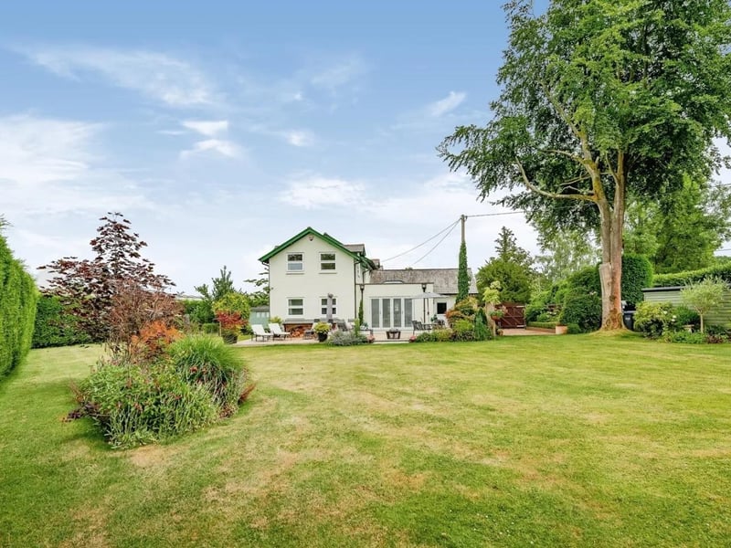 The landscaped rear garden features a patio and decked area leading to large lawned garden