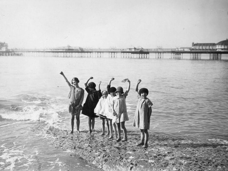 Young girls waving from the water's edge on Brighton beach on 10th March 1929: