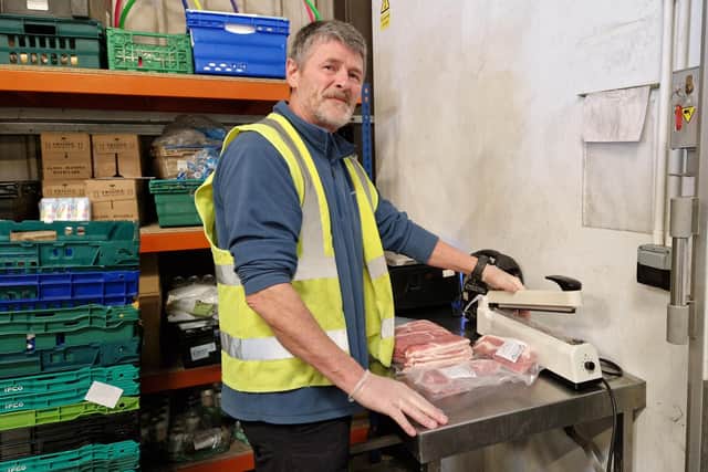 Nigel Boshein, food hub manager, breaking up bulk packs of bacon into smaller packages for the food hubs