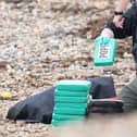 Armed offices surround suspected drug packages which washed up on the beach in Ferring. Photo: Eddie Mitchell