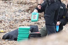 Armed offices surround suspected drug packages which washed up on the beach in Ferring. Photo: Eddie Mitchell