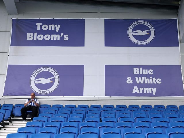 A fan of Brighton & Hove Albion sits in the stand, under a flag which reads "Tony Bloom's Blue & White Army", prior to the Premier League match between Brighton & Hove Albion FC and Leicester City FC at Amex Stadium