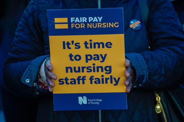 A healthcare workers holds a placard at a picket line outside St Thomas' Hospital in London on December 20, 2022. - UK nurses staged a second unprecedented strike amid an increasingly acrimonious fight with the government for better wages and warnings that patient safety could be jeopardised. (Photo by Niklas HALLE'N / AFP) (Photo by NIKLAS HALLE'N/AFP via Getty Images)
