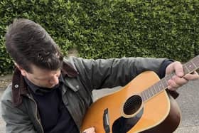 Jamie T signs an acoustic guitar ahead of a charity raffle.