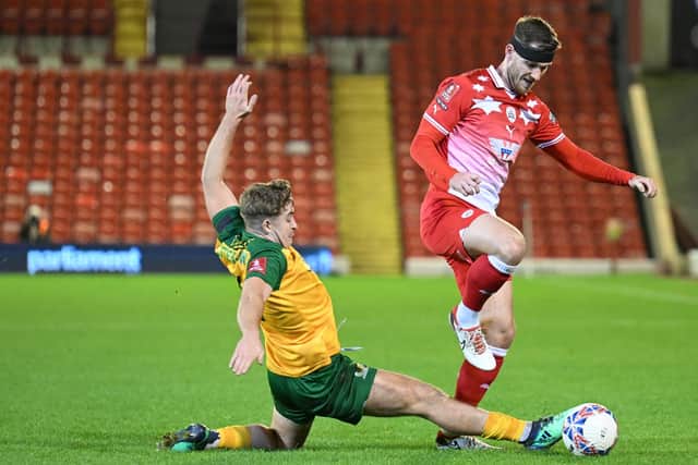BARNSLEY, ENGLAND - NOVEMBER 03:  Charlie Hester-Cook of Horsham challenges Jamie McCart of Barnsley for the ball during the Emirates FA Cup First Round match between Barnsley and Horsham at Oakwell Stadium on November 03, 2023 in Barnsley, England. (Photo by Ben Roberts Photo/Getty Images)