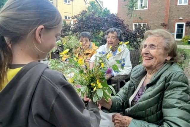 Wellington Grange resident Valerie Woodall is all smiles as she discusses flower arranging with one of the young visitors from 10th Chichester Brownies