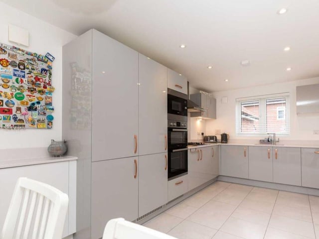 The kitchen/dining room has a range of wall and base cabinets finished in a modern and contemporary gloss design with complementing quartz work surfaces running through. There is a selection of integrated appliances, tiled flooring and ample space for a dining table.
