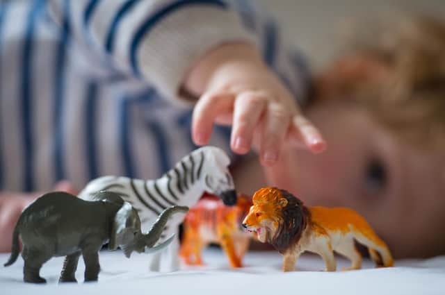 A preschool age child plays with plastic toy animals.