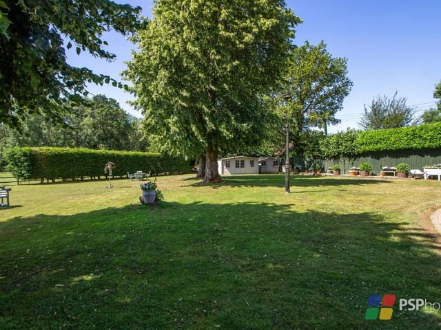 The home sits on an 0.8 acre plot with level lawn, established borders and trees
