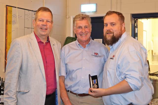 Olly Clarke, right, receives his long-service medal from Mike McCartain, left, and Nick White. Credit: RNLI/Beth Brooks