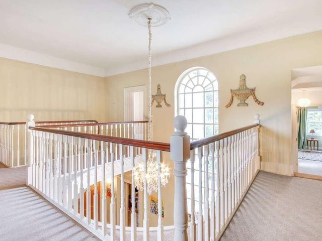 A beautiful turned staircase rises to a horseshoe gallery on the first floor