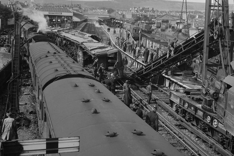 Investigators and firemen at the scene of a rail crash in front an overturned train and a large piece of debris being lifted by a crane outside the railway station. (Photo by Evening Standard/Hulton Archive/Getty Images)
