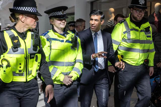 Prime Minister Rishi Sunak speaks with police officers as they walk in the corridors of the Swan Walk shopping centre during a visit in Horsham. (Photo by RICHARD POHLE/POOL/AFP via Getty Images)