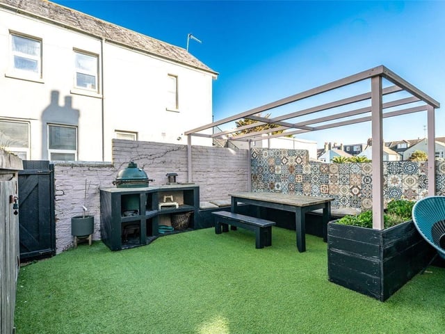 The garden is mostly laid to low-maintenance artificial grass, enhanced by raised flower beds