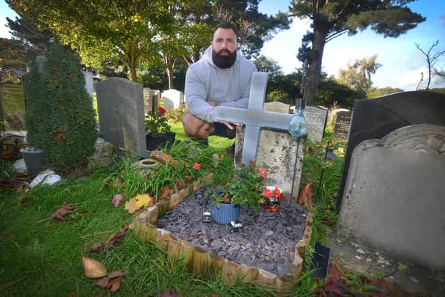 Craig Willard with his father's grave and ceramic cross in Bexhill Cemetery.