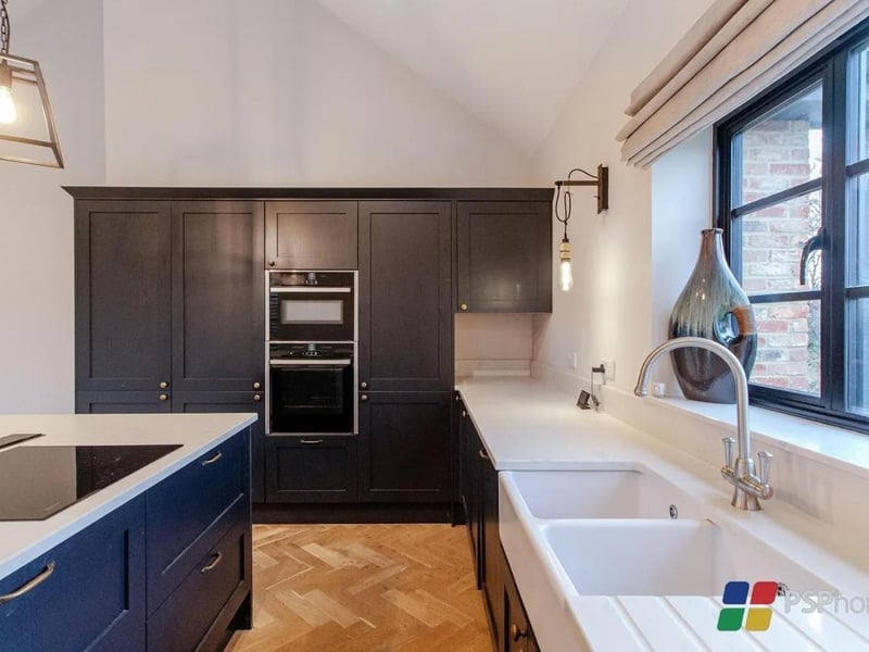 The kitchen is shaker-style with a range of wall and base units, as well as white Quartz worktops and integrated Neff appliances
