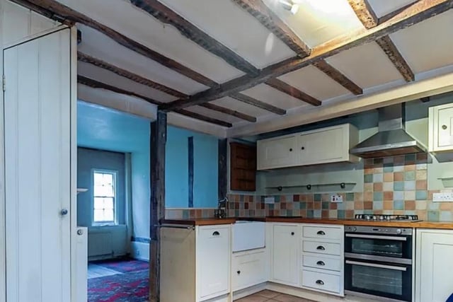The kitchen has a tiled floor and wooden beams