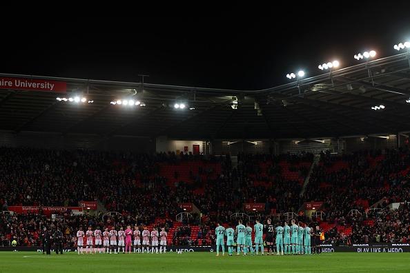 Players of Stoke City and Brighton & Hove Albion applaud as a tribute to the late English Football Commentator John Motson, who passed away at the age of 77