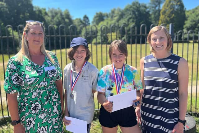 From left to right Lizzie Robinson-Charlton (Gatwick Airport) presents the 2 winning pupils with boarding pass and medals, and Class 3 teacher Katie Foley from Atelier 21