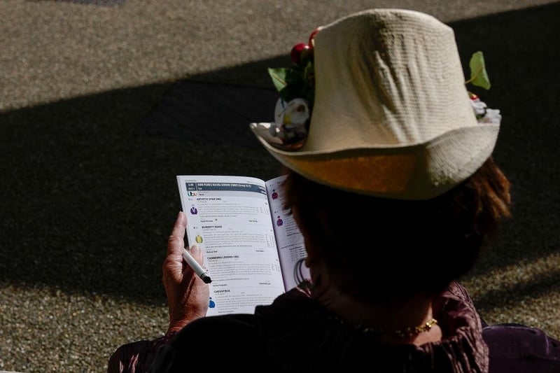CHICHESTER, ENGLAND - AUGUST 03: Reading the Timeform racecard at Goodwood Racecourse on August 03, 2023 in Chichester, England. (Photo by Alan Crowhurst/Getty Images):Images from Ladies' Day, Glorious Goodwood 2023