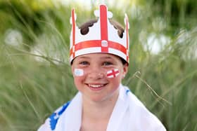 An England fan wearing a hat poses for a photo outside the Brighton & Hove Community Stadium.