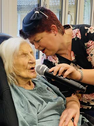 Betty Grey singing her favourite song 'The White Cliffs of Dover' with her favourite entertainer, Tania, who regularly sings for the home