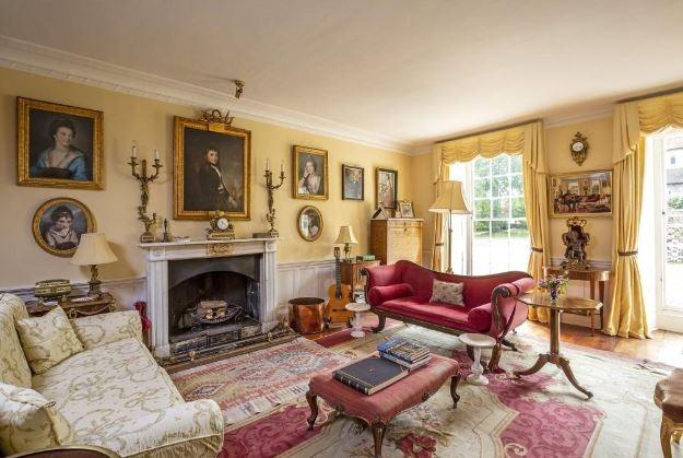 The drawing room is heated by the open fireplace with its ornate marble mantelpiece and cast iron firebasket; the room is partially wood panelled.