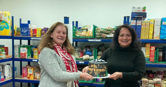 Sheila Kirkham, Editor of rh fourteen, presents their 17 th birthday cake to Amalia Lovett at Horsham District Food Bank.