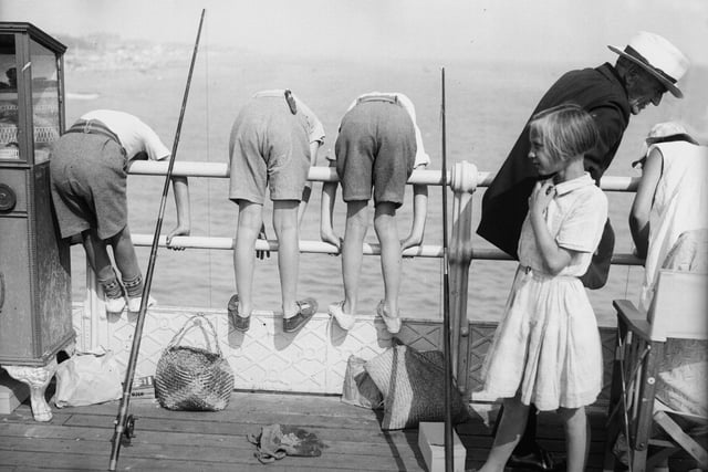 A row of boys lean far over the railings during a children's angling contest at Worthing in August 1935