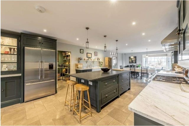 The impressive open plan kitchen/dining room and family area is the heart of the home. In the centre is a stunning bespoke solid wood kitchen providing an excellent range of painted cabinets complemented by carrera marble worktops and a dark limestone central island