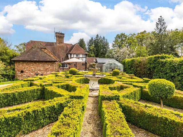 The box-hedge parterre has a classic tiered stone fountain as its centrepiece.