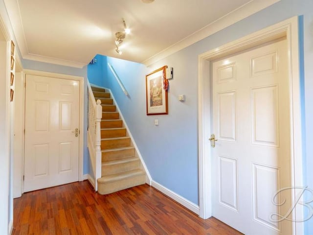 To move up to the first floor, we must return to the spacious entrance hallway, with its laminate floor, central heating radiator and carpeted staircase.
