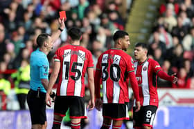 Referee Stuart Attwell shows a red card to Mason Holgate of Sheffield United after a VAR review during the Premier League match between Sheffield United and Brighton & Hove Albion at Bramall Lane on February 18, 2024 in Sheffield, England. (Photo by David Rogers/Getty Images)