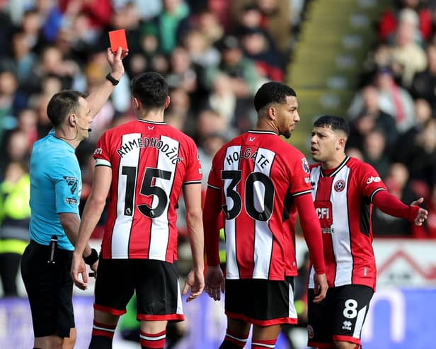 Referee Stuart Attwell shows a red card to Mason Holgate of Sheffield United after a VAR review during the Premier League match between Sheffield United and Brighton & Hove Albion at Bramall Lane on February 18, 2024 in Sheffield, England. (Photo by David Rogers/Getty Images)