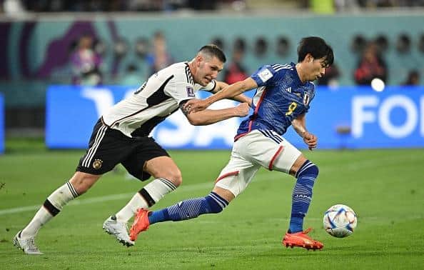 Niklas Süle of Germany challenges Kaoru Mitoma of Japan during the World Cup Group E at the Khalifa International Stadium